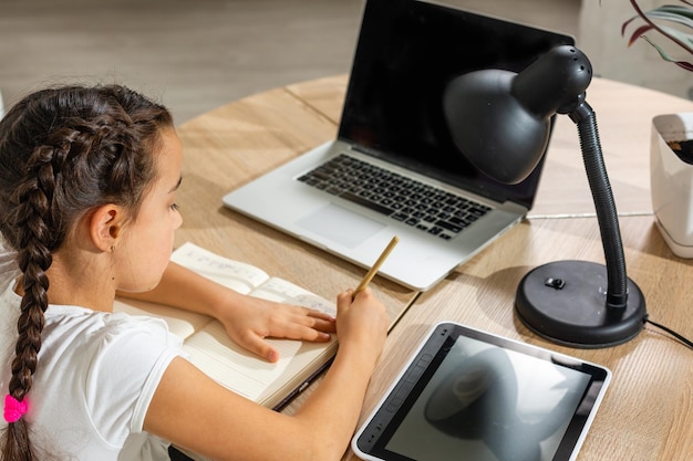 Little girl kid studen estudiando clases en línea con laptop en casa, nueva normalidad. Coronavirus Covid-19. Distanciamiento social, educación en casa.