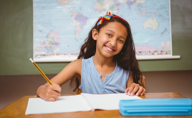 Little girl writing book in classroom