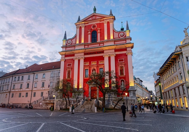 Liubliana, Eslovênia - 27 de abril de 2018: Igreja Franciscana da Anunciação e pessoas na Praça Preseren em Liubliana, na Eslovênia. Tarde da noite