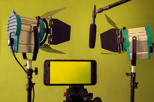 Live Stream Video Multimedia Concept smartphone micrófono y reflectores en el fondo verde