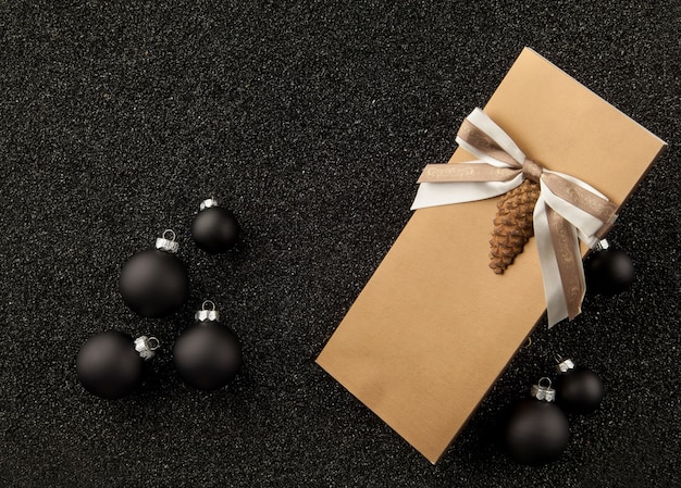 Livreto de presente com decorações para árvores de natal em um fundo preto granulado
