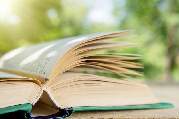 Livro aberto em uma mesa de madeira em um jardim Dia ensolarado de verão lendo em um conceito de férias