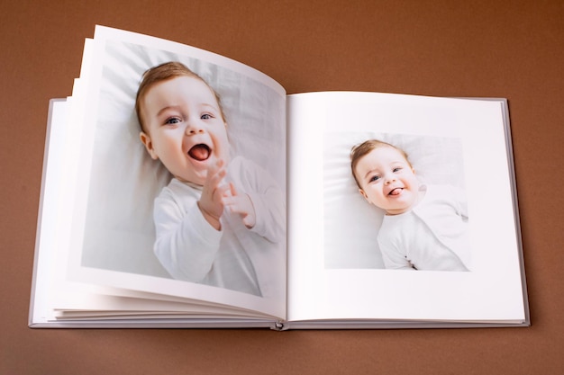 Livro de fotos do bebê em fundo marrom, retrato emocional infantil, menino bonito da criança