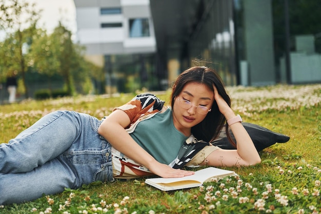 Livro de leitura A jovem asiática está ao ar livre durante o dia