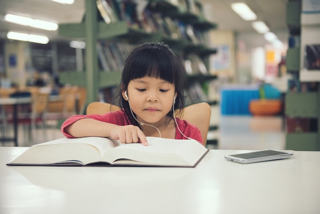 Livro de leitura de menina de crianças na sala da biblioteca