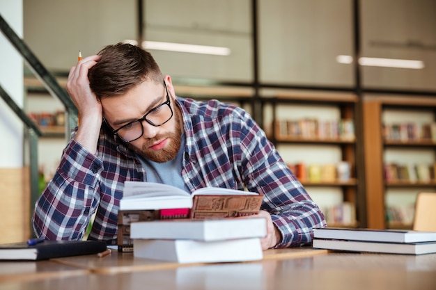 Livro de leitura do jovem rapaz com cara séria