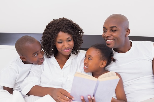 Livro de leitura feliz da família junto na cama