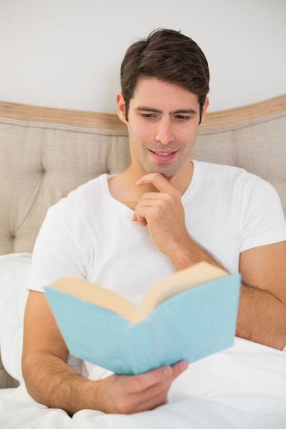 Livro de leitura jovem relaxado na cama