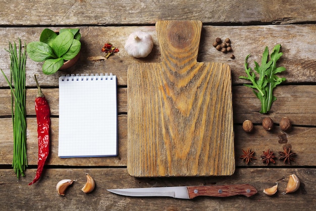 Livro de receitas aberto com ervas frescas e especiarias em fundo de madeira