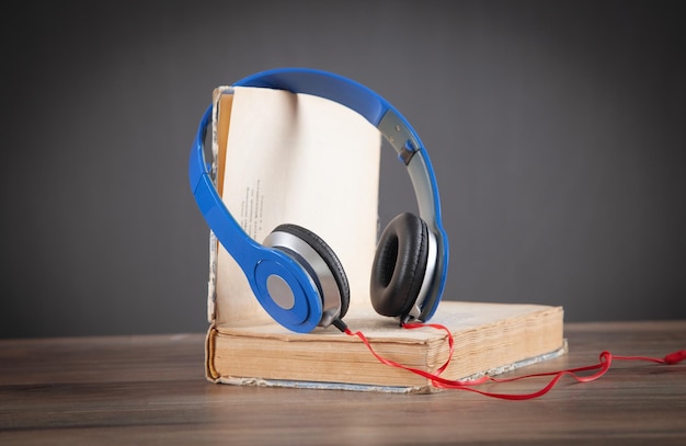 Livro e fones de ouvido na mesa de madeira Audiobook