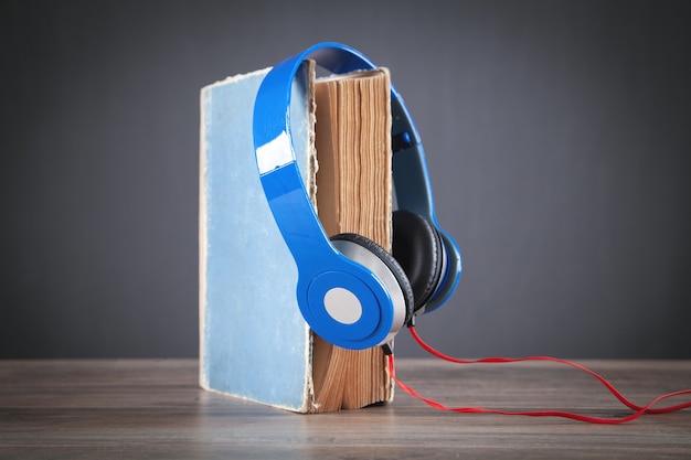 Livro e fones de ouvido na mesa de madeira. Áudio-livro