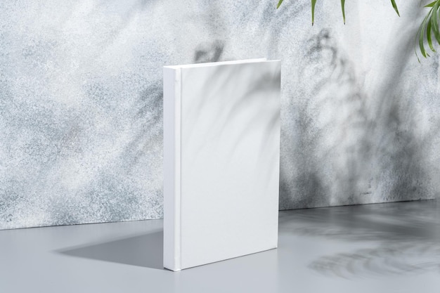 Livro em branco com capa dura em fundo cinza com sombras