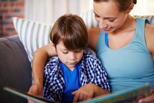 Livro em casa e mãe com filho menino ou passatempo com atividade ou ligação juntos no salão Apartamento familiar ou mãe com filho desenvolvimento criativo ou infantil com leitura ou narrativa com educação