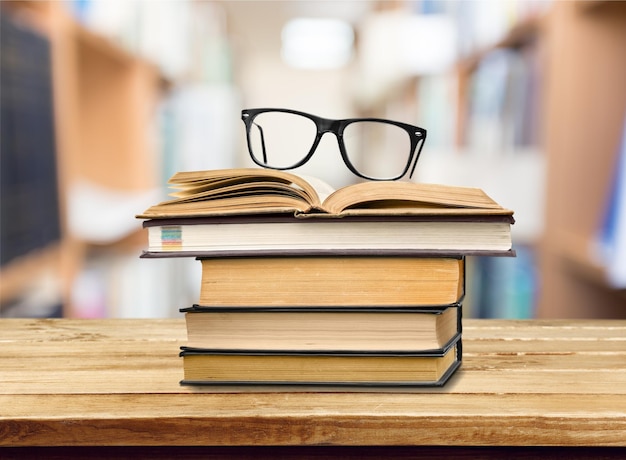 Livro na biblioteca com livro antigo aberto, pilha de arquivos de literatura na mesa de leitura,