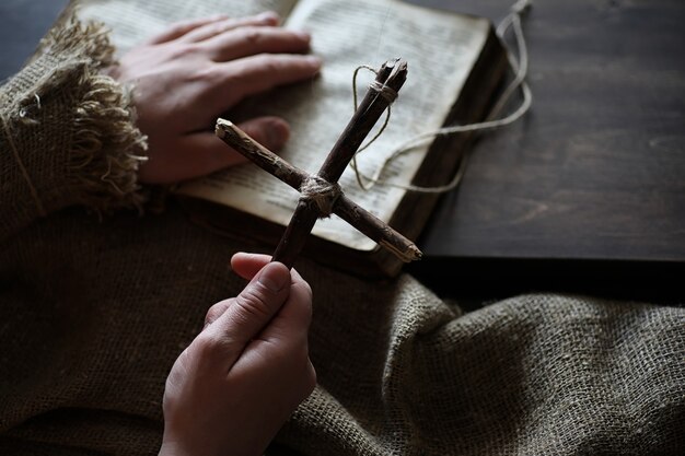 Livro religioso antigo e cruz de madeira no fundo de uma madeira e serapilheira