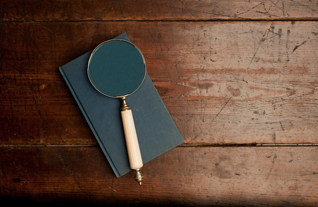 livro vintage azul com lupa óptica na velha mesa de madeira