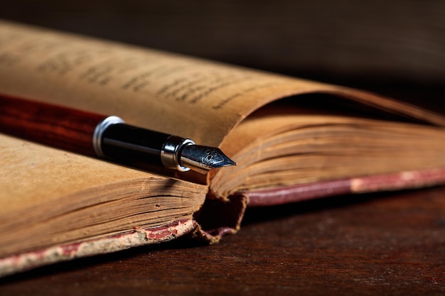 Livro vintage e caneta de tinta em uma mesa de madeira