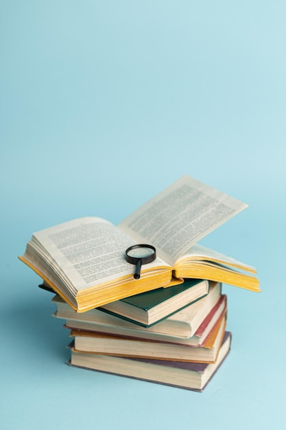 Livro vintage e lupa sobre fundo azul claro Fundo de educação Dia mundial dos livros