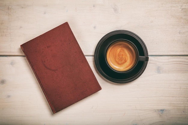 Livro vintage e uma xícara de café no fundo de madeira