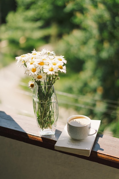 Livro xícara de café e camomila branca em uma janela de madeira Conceito romântico Estilo vintage