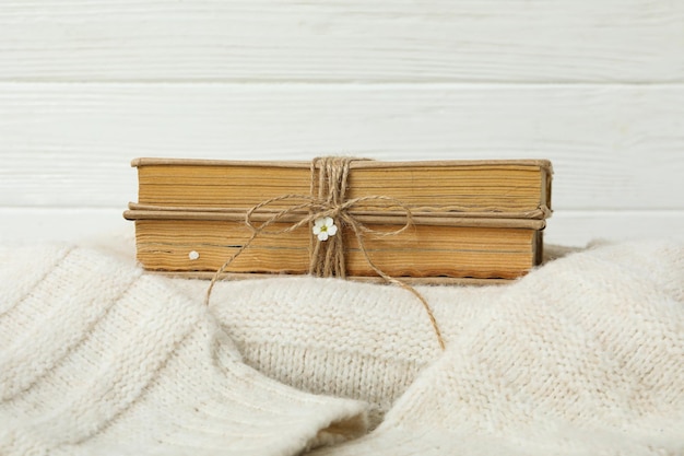 Livros amarrados com barbante na blusa sobre fundo branco de madeira