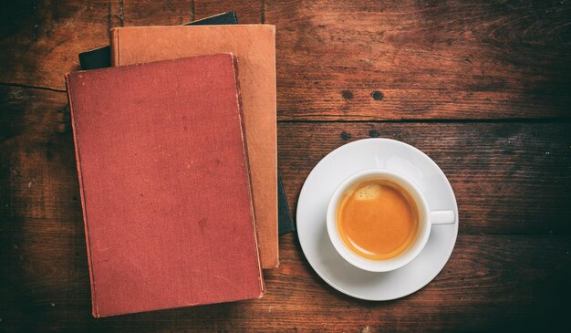 Livros antigos e uma xícara de café em fundo de madeira