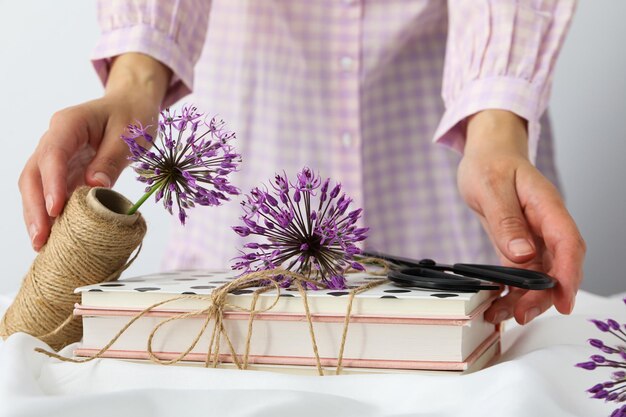 Livros de flores e barbante em mãos femininas em fundo branco