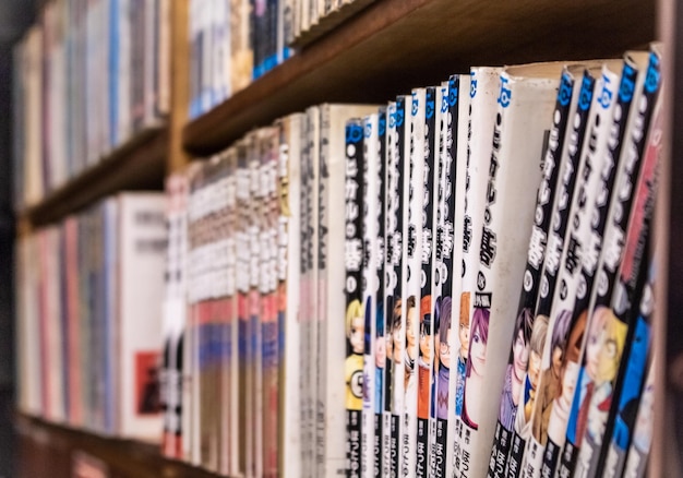 Livros de mangá japoneses alinhados na prateleira da livraria.