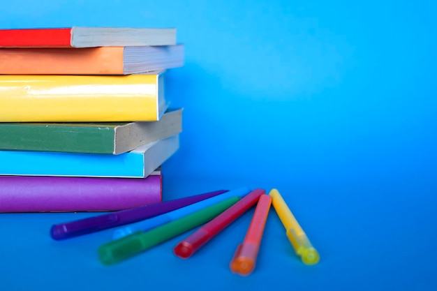 Livros empilhados com as cores da bandeira lgtb e canetas da mesma cor em um fundo azul com espaço de cópia Horizontal