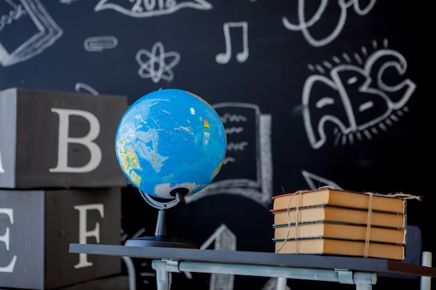 Foto livros escolares e globo do mundo na mesa da escola