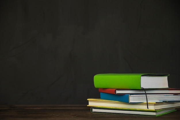 Foto livros gráficos na mesa perto da parede preta