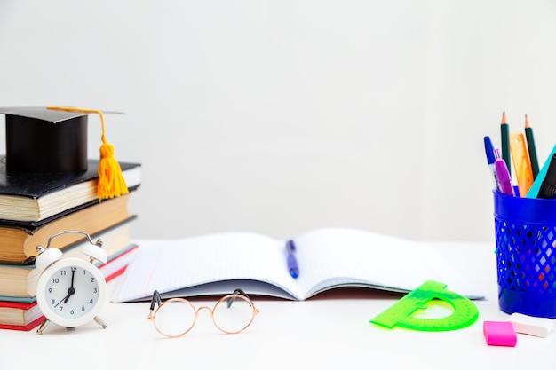 Livros, materiais de escrita, óculos, caderno e despertador na área de trabalho. de volta à escola. conceito de aprendizagem e autoeducação.