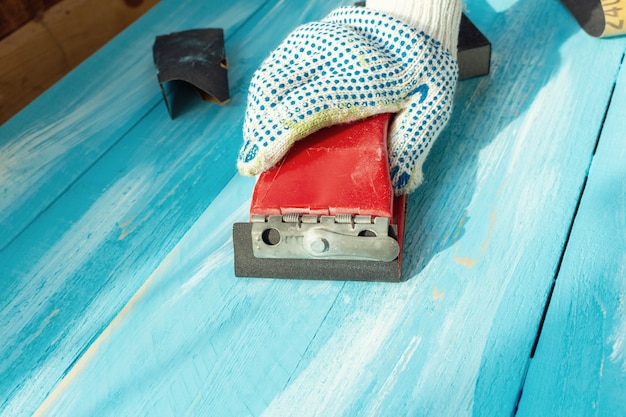 Lixar com abrasivos em uma mesa de madeira pintada de madeira azul de mão