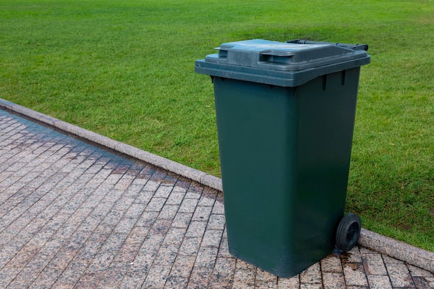 Lixeira de plástico reciclável com rodas verdes ao lado da estrada para coleta de lixo. Fechar-se