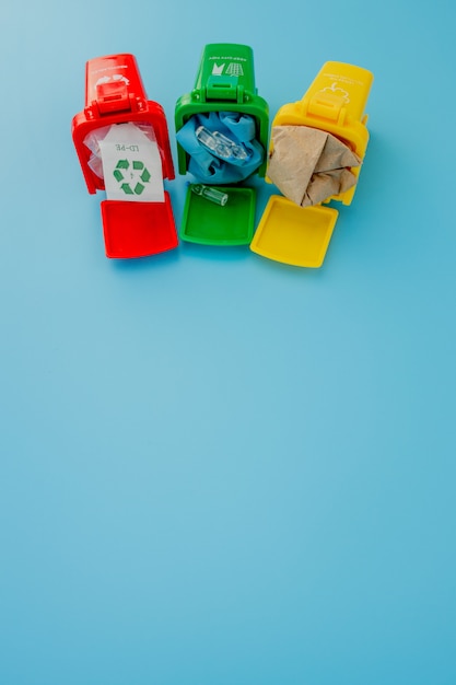 Foto lixeiras amarelas, verdes e vermelhas com recicl o símbolo no fundo azul. mantenha a cidade arrumada. deixa o símbolo de reciclagem. conceito de proteção da natureza