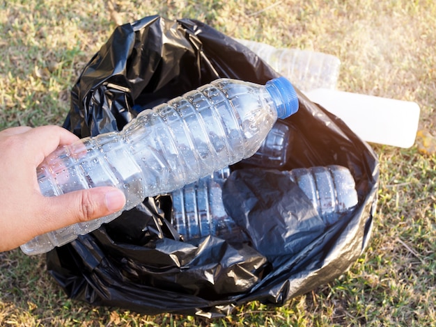 Lixo de coleta asiáticos com plástico reciclar garrafas de água em saco de lixo preto. os voluntários protegem o ambiente limpando o parque e a natureza.