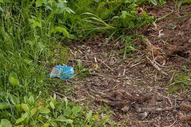 Lixo na forma de um saco plástico de cor azul contra o fundo da natureza e da grama verde