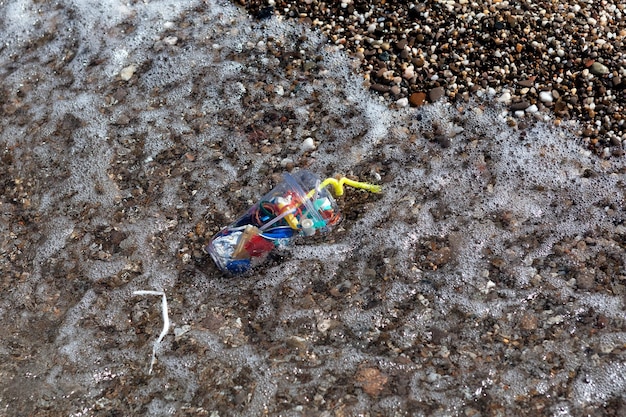 Lixo plástico doméstico na ressaca do mar Poluição de resíduos plásticos da área da água