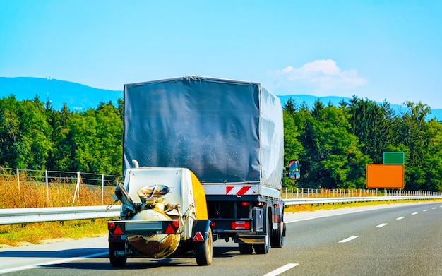 LKW-Anhänger mit niedrigem Schleppseil auf der Straße. Auto Fahrzeug mit Carrier Transporter Schlepper auf der Auffahrt. Europäische Transportlogistik im Speditionsbetrieb. Auf der Autobahn schleppen.