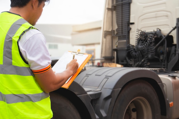 LKW-Fahrer, der tägliche Checkliste der Sicherheit den halb LKW kontrolliert