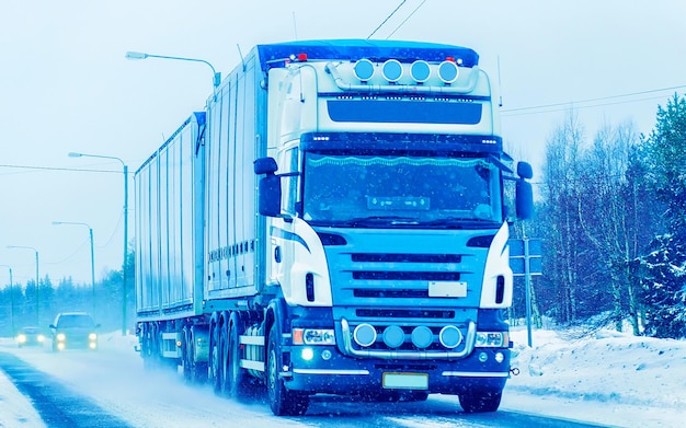 LKW in der Schneewinterstraße von Finnland. Trucker auf der Autobahn. LKW, der Logistikarbeiten erledigt. Auflieger mit Fahrer. Große Frachtwagenfahrt. Frachtversand. Transport Exportindustrie. Container mit Waren