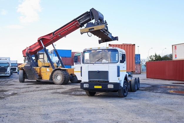 LKW-Logistik und Lieferkette mit einem Baufahrer auf einem gewerblichen Containerhof für den Versand oder die Verteilung Lagerbestand und Fracht mit einem Fahrzeug in der Import- und Exportindustrie