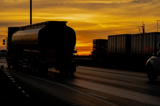 LKW mit Cargo, der bei Sonnenuntergang im Sommer auf Straßentransportautobahn fährt
