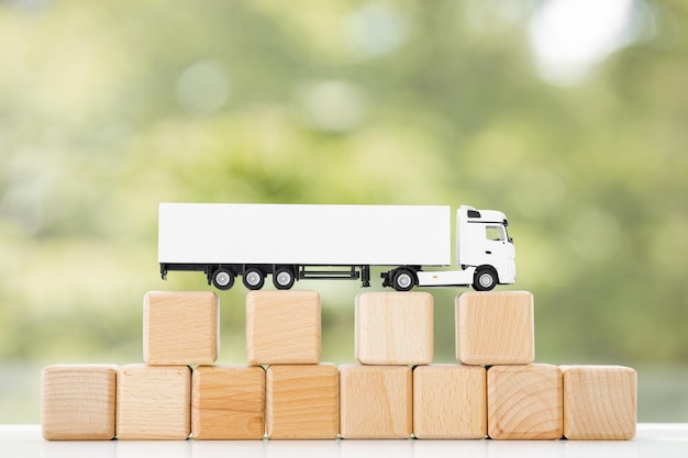 LKW mit Holzwürfeln isoliert auf grünem Sommerhintergrund Logistik- und Großhandelskonzept