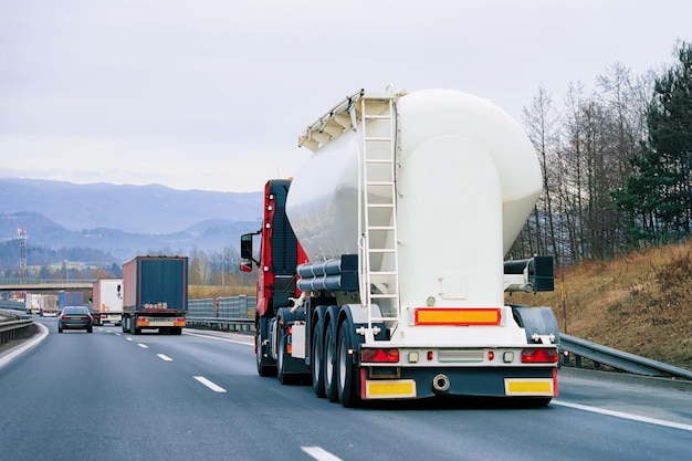 LKW mit Zisterne auf der Straße. Trucker auf der Autobahn. LKW, der Logistikarbeiten erledigt. Auflieger mit Fahrer. Großer Frachtwagen. Frachtversand. Transport Exportindustrie. Container mit geladener Ware