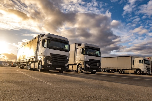 LKWs in Folge mit Containern auf dem Parkplatz Logistik- und Transportkonzept