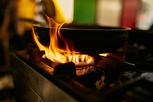 llama en la sartén Chef profesional hace flambeado para comida en la cocina del restaurante