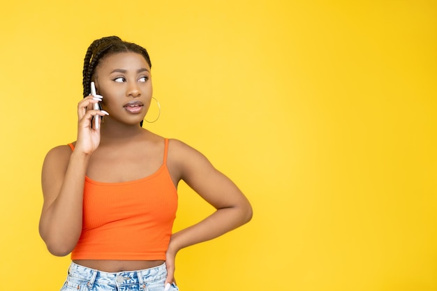 Llamada telefónica Comunicación móvil Conexión celular Mujer africana interesada hablando por teléfono inteligente aislada en el fondo del espacio de copia naranja
