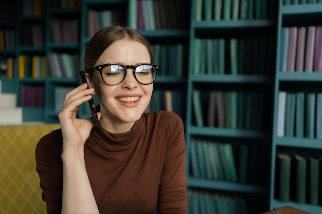 Llamada telefónica Mujer financiera que trabaja en el lugar del informe de la oficina Un estudiante con gafas en la biblioteca