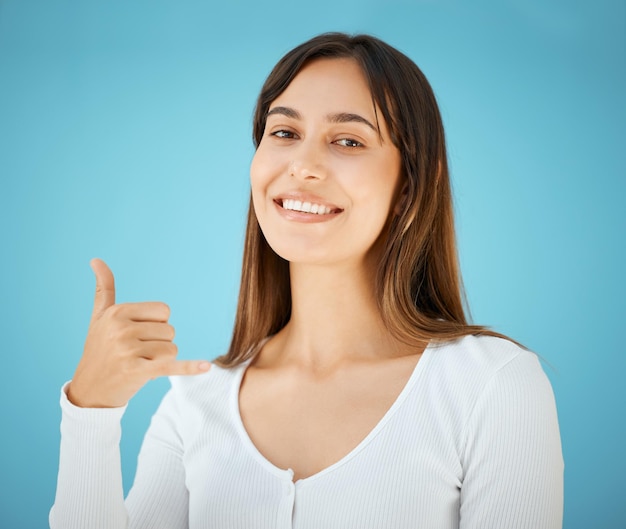 Foto llámame foto de estudio de una mujer joven sosteniendo su mano y mostrando el cartel de colgar diez